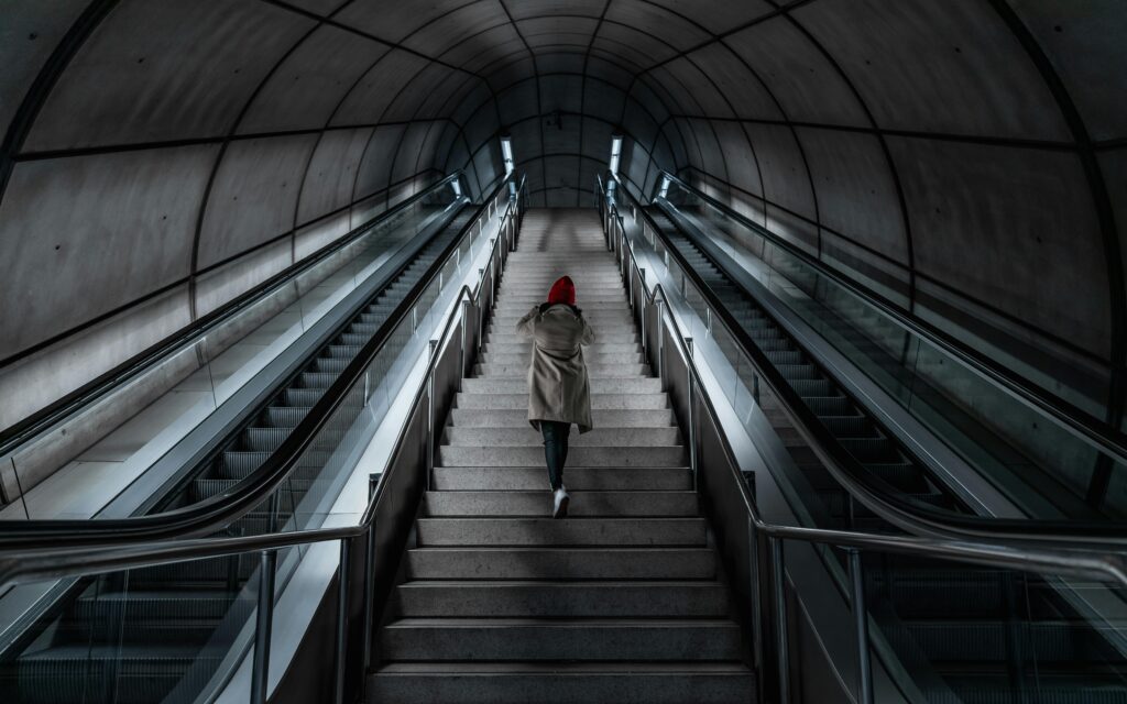 A person ascends stairs in a modern metro station tunnel in Bilbao, Spain.